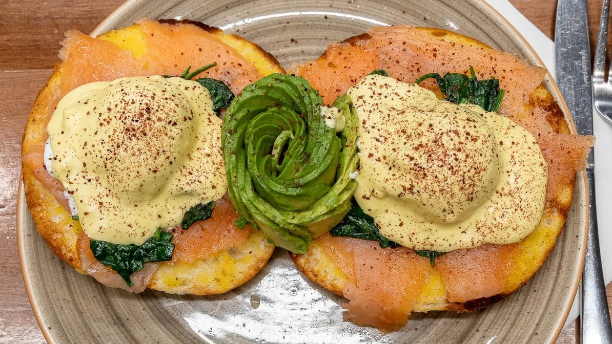 Salmon eggs Benedict with avocado rose and hollandaise on golden hash cakes